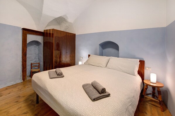 A bedroom with a large bed, wooden wardrobe, and a small bedside table with a lamp. - Apartment 'Casa Bianca' with Mountain View (Bormio)