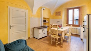 Een kleine keuken met een eettafel, stoelen, een witte kookplaat en een koelkast.