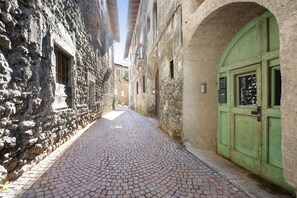 A narrow cobblestone street flanked by historic stone buildings with arched doorways and windows. - Apartment 'Casa Bianca' with Mountain View (Bormio)