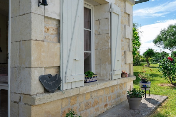 A stone building with a window, a potted plant, and a small table with a flower pot.