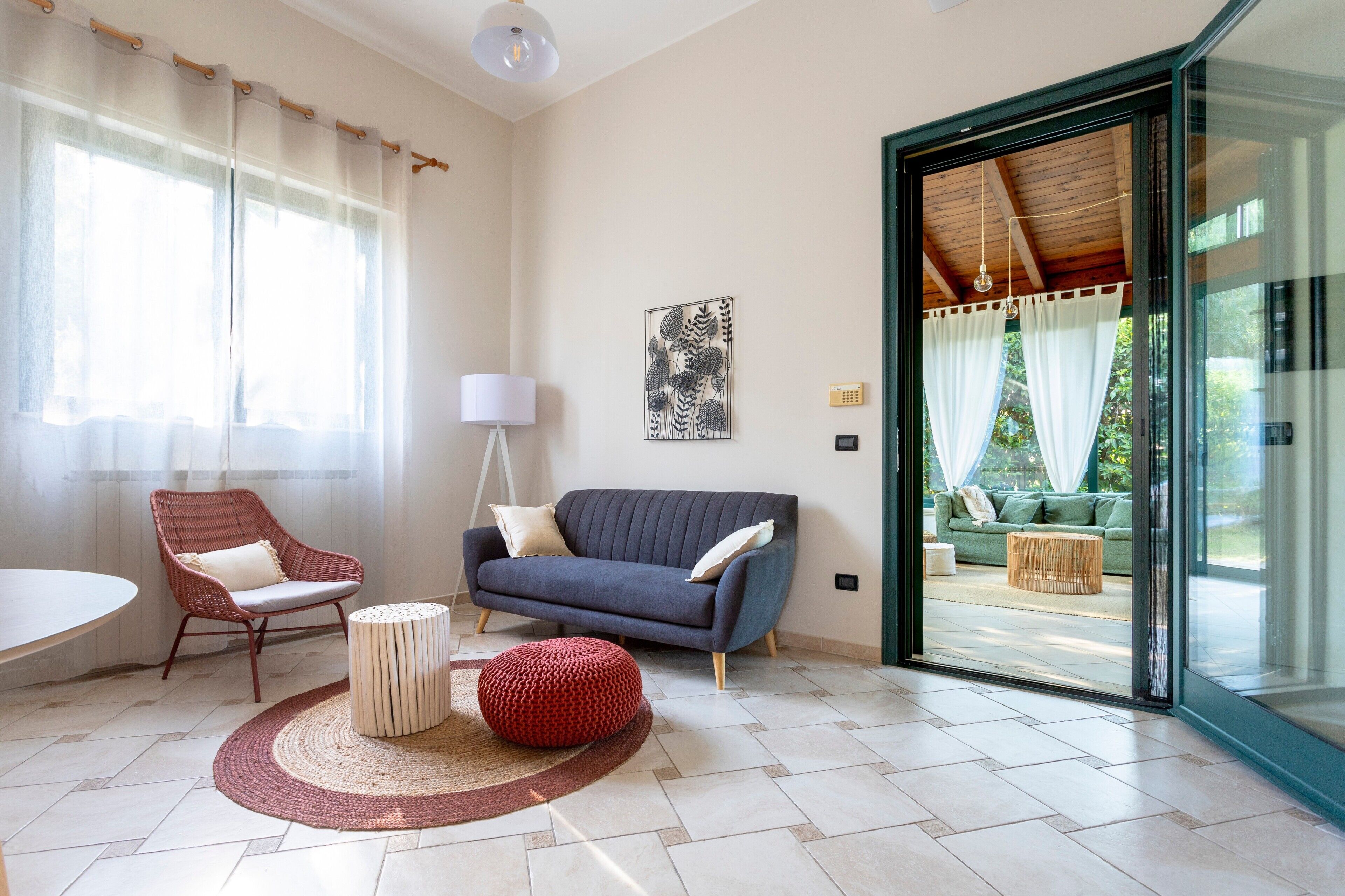 Un salon moderne avec un canapé, un fauteuil et un pouf, une lampe et un tableau au mur.