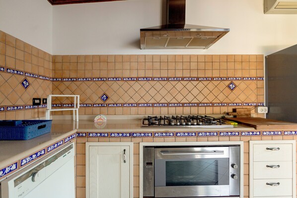 Una cocina con horno empotrado, estufa a gas y extractor.