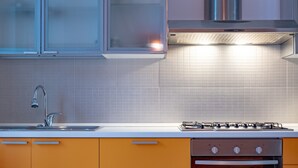 A modern kitchen with a stainless steel sink, a gas stove, and orange cabinets.