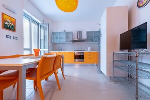 A modern kitchen with a dining area, a TV, and a large window.
