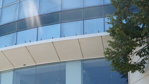 A modern building with a glass facade, a green wall with plants, and a set of stairs leading to the entrance. - MILLENNIUM (Constanta)