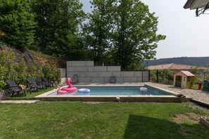 A backyard with a swimming pool, lounge chairs, and a small playhouse. - Apartment "Gîte les Monteils" with Mountain View, Private Terrace & A/C (Vesseaux)