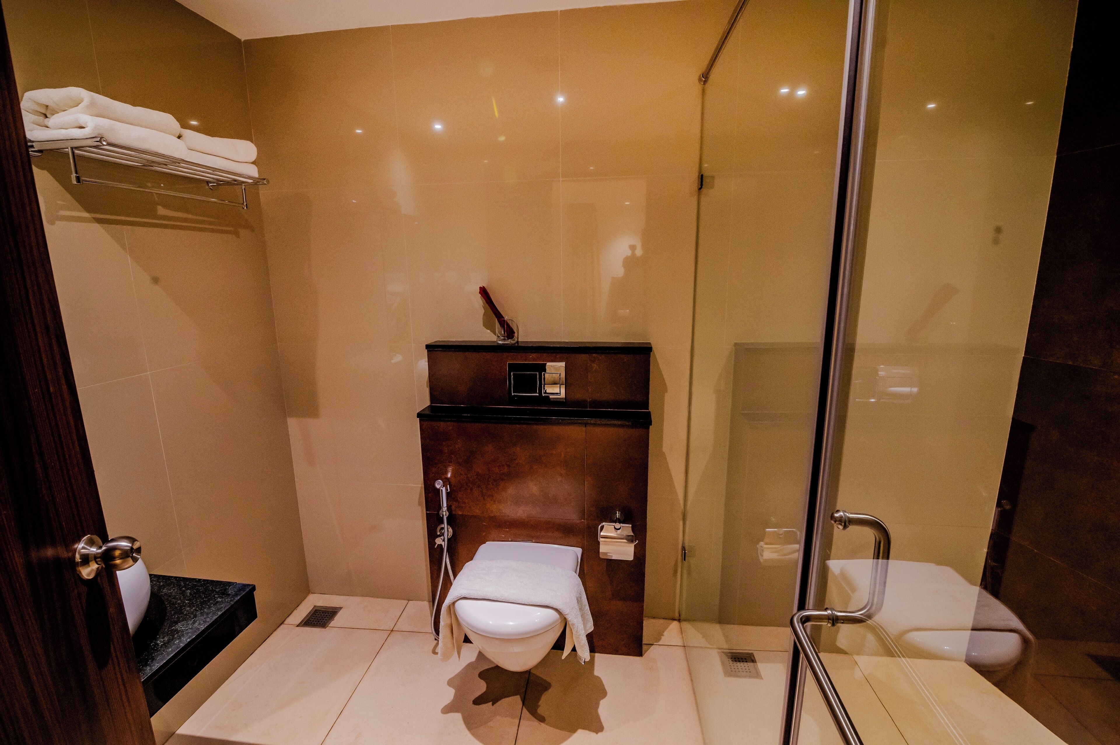 Ein modernes Badezimmer mit einer Duschkabine aus Glas, einem Holzbidet und einer Toilette.