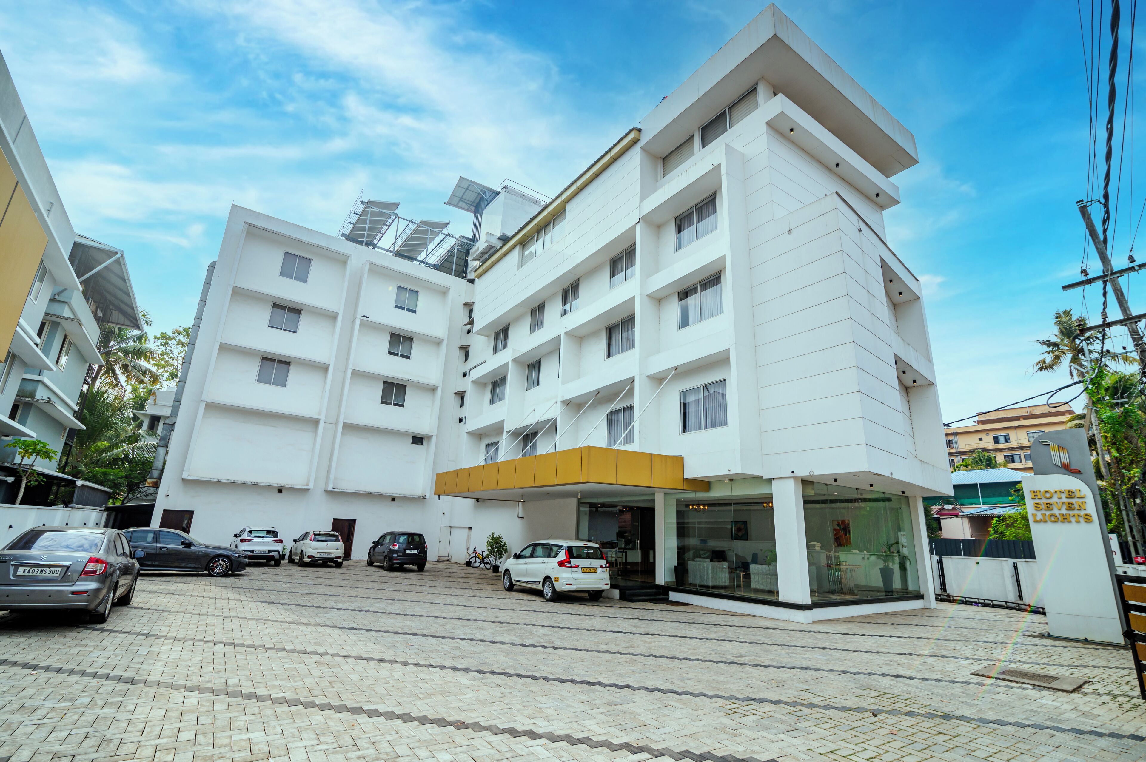 A modern hotel with a white facade, multiple floors, and a covered entrance.