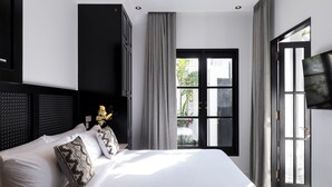 A modern hotel room with a large bed, a flat-screen TV, and a view of the outdoors through a large window. - Villa Martini Beachside 4 (Canggu)
