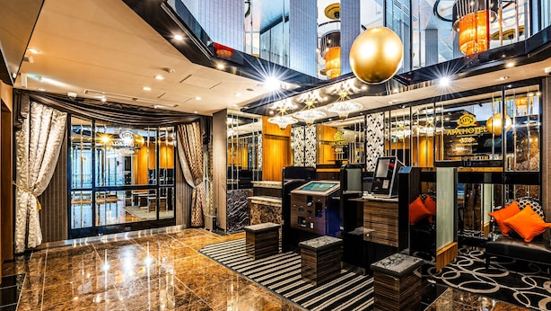 A modern lobby with a marble floor, a reception desk, and a seating area with orange cushions. - APA Hotel Hatchobori Ekimae (Tokyo)