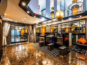 A modern lobby with a marble floor, a reception desk, and a seating area with orange cushions. - APA Hotel Hatchobori Ekimae (Tokyo)