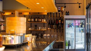 Un espace bar doté d’un long comptoir, d’étagères remplies de bouteilles et d’un réfrigérateur bien garni de boissons.