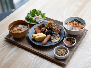 A wooden tray with various Japanese dishes including a bowl of soup, a plate with vegetables, meat, and fish, and a bowl of rice with seaweed. - APA Hotel Hatchobori Ekimae (Tokyo)