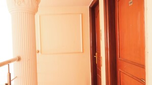 Un pasillo con suelo de mármol, una columna blanca y una puerta de madera.