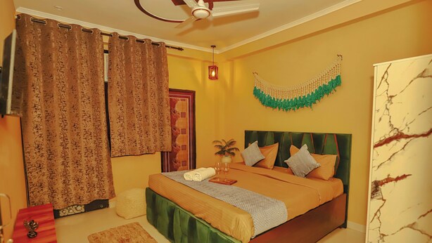 Un dormitorio con cama, cortinas, ventilador de techo, decoración en la pared y mesita de noche.
