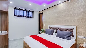 A hotel room with a bed, a wardrobe, a window with curtains, and a patterned wall. - Roomshala 089 Green Palace (New Delhi)