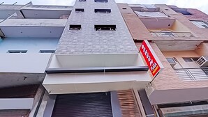 A multi-story building with a flat roof and several windows. There is a sign on the right side of the building that reads "ORIGINAL PLAZA." - Roomshala 089 Green Palace (New Delhi)