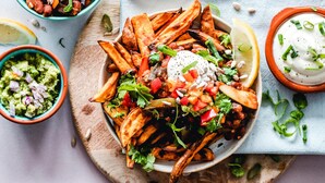 A plate of nachos topped with cheese, jalapeños, and sour cream, accompanied by guacamole and a side of salsa. - Roomshala 089 Green Palace (New Delhi)