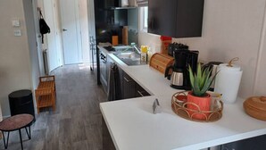 A modern kitchen with a central island, a built-in oven, and a large window. - Cottage with a large garden (Hoenderloo)