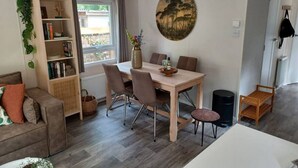 A modern living room with a dining table, sofa, bookshelf, and a painting on the wall. - Cottage with a large garden (Hoenderloo)