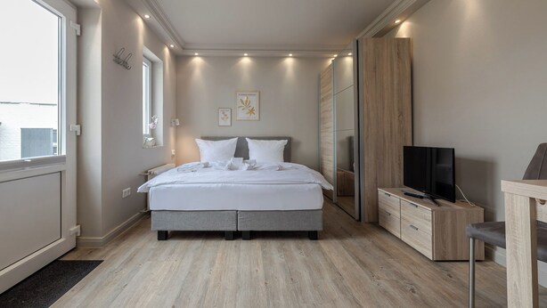Une chambre à coucher moderne avec un grand lit, une télévision et une armoire en bois.