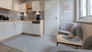 Une cuisine moderne avec des meubles blancs, une machine à café et un coin repas comprenant une table et des chaises.