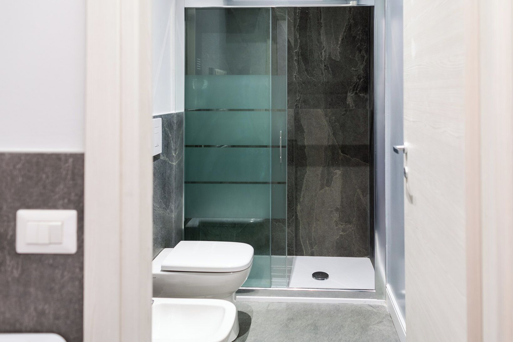 Ein kleines Badezimmer mit Duschkabine aus Glas, Toilette und Bidet.