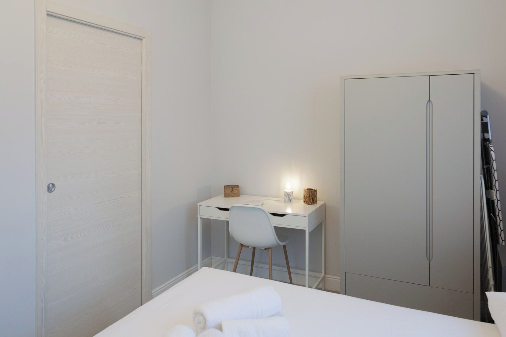 Quarto com cama, escrivaninha, cadeira e guarda-roupa.