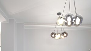 Uma área de jantar moderna com uma mesa redonda, cadeiras brancas e um sofá cinza escuro.