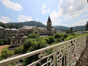 Un bâtiment historique doté d’une tour imposante, entouré d’une végétation luxuriante et surplombé d’un ciel dégagé.