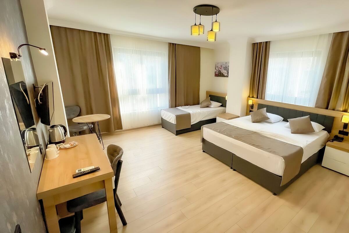 A hotel room with two beds, a desk with a chair, a coffee maker, and a TV.