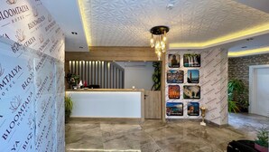 A hotel reception area with a modern design, featuring a reception desk, a patterned ceiling, and a wall adorned with framed pictures of landmarks. - Bloomtalya Hotel  (Antalya)