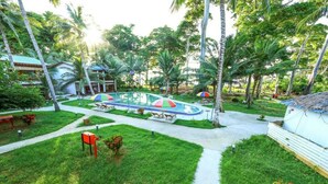 A resort with a pool area surrounded by palm trees and a pathway leading to the pool. - Pearl Park Beach Resort Private Limited (Port Blair)