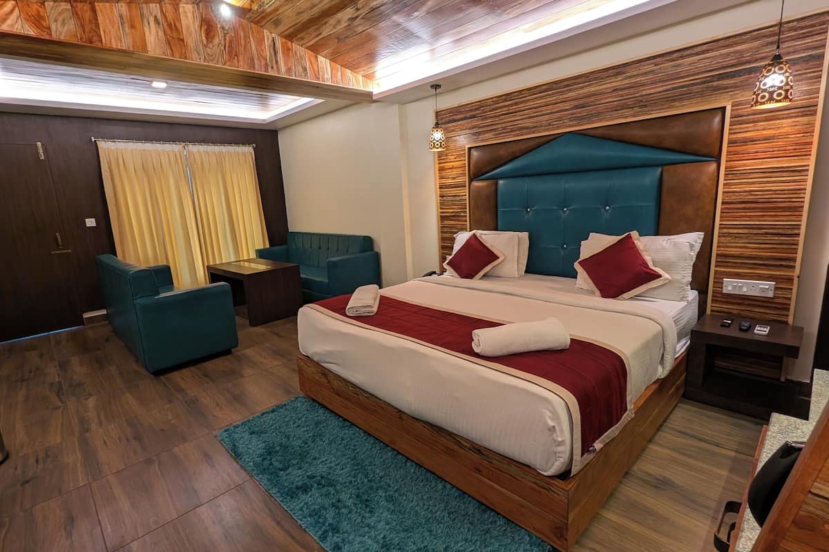 Une chambre moderne avec une tête de lit en bois, un grand lit avec une literie rouge, un canapé bleu et une petite table.