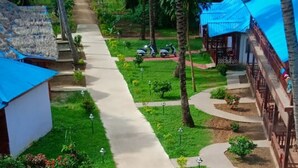 A pathway lined with palm trees leading to a beach, with a building on the left and a covered structure on the right. - Pearl Park Beach Resort Private Limited (Port Blair)