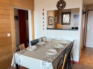 A dining area with a table set for four, wooden walls, a mirror, and holiday decorations. - Apartment for 6/7 pers, mountain view, small pets welcome (Avoriaz)