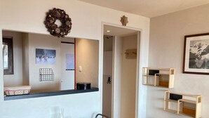 Un comedor con una mesa preparada para cuatro personas, un espejo sobre la mesa y un cuadro en la pared.