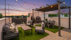 Ein Außenbereich mit Terrasse, Lichterketten, einer Pergola, Sitzgelegenheiten und einem Esstisch.