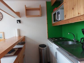 Eine kleine Küche mit Holzböden, einer Mikrowelle, einem Spülbecken und einem Geschirrspüler.