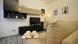 A modern living room with a flat-screen TV, a sofa, and a coffee table with cups. - Papireto 11 Loft |Charming cozy space at Cathedral (Palermo)