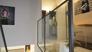 A modern interior with a glass railing staircase, a flat-screen TV, and a minimalist decor. - Papireto 11 Loft |Charming cozy space at Cathedral (Palermo)