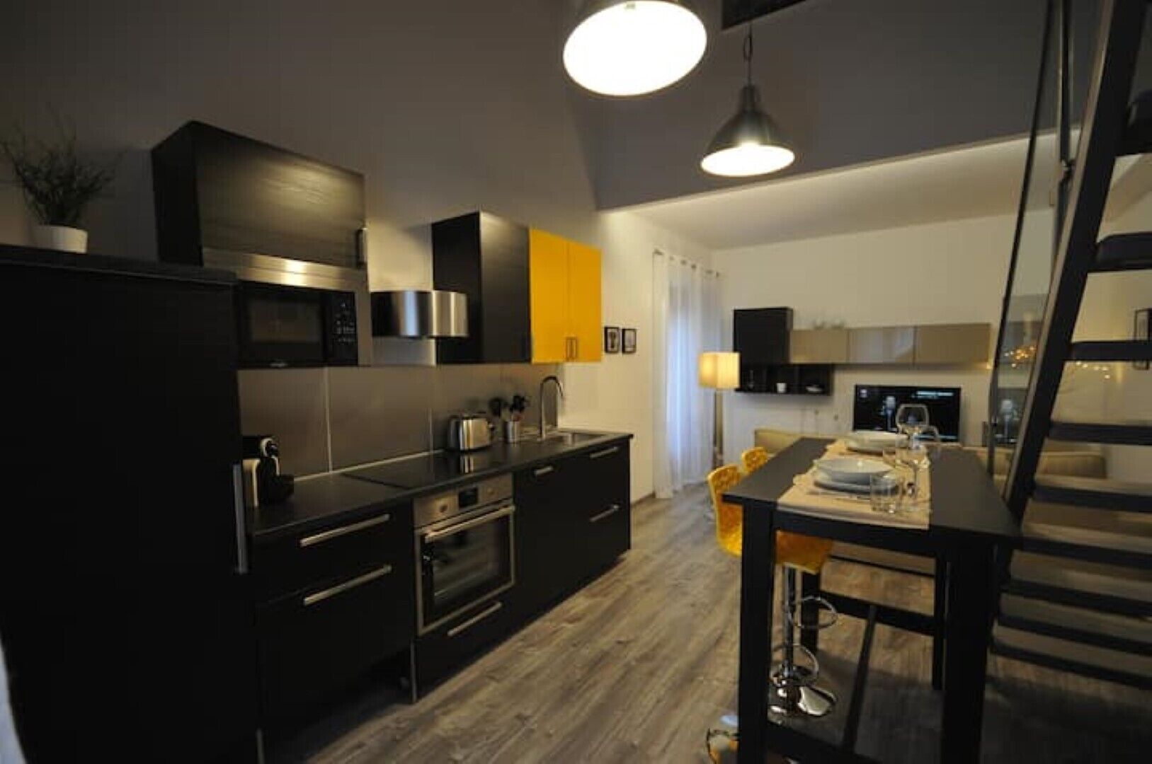 Una cocina moderna con gabinetes negros, electrodomésticos de acero inoxidable y un comedor con mesa y sillas.