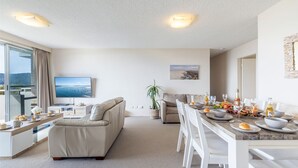Een moderne woonkamer met een bank, eettafel en een televisie.