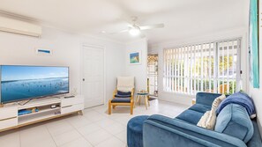 Relax in this stylish living room with a large flat-screen TV, comfortable sofa, and a wooden chair.