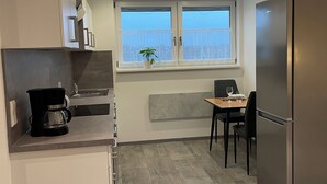 A modern kitchen with a built-in refrigerator, a coffee maker, and a dining area with a table and chairs.
