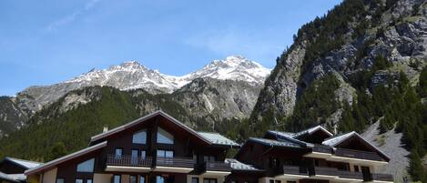Un hôtel à plusieurs étages, doté de balcons, qui se dresse sur fond de montagnes enneigées.