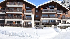 A multi-story wooden building with balconies, surrounded by snow and mountains.