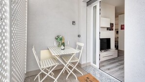 A small, enclosed balcony with a white metal table and chairs, a bottle of champagne, and a small vase with flowers. - BnButler - Archimede 53 (Milan)