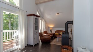 A spacious living area with a fireplace, a sofa, and a dining table. - 3-zi-fewo für Max. 4 Pers. im DG, Wlan, Strandnah (Graal-Müritz)