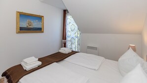 A bedroom with a bed, a painting of a sailboat, a window with curtains, and a bedside lamp. - 3-zi-fewo für Max. 4 Pers. im DG, Wlan, Strandnah (Graal-Müritz)
